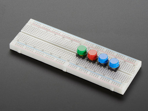 Top-down shot of 15 colorful round tactile button switches in green, yellow, red, blue, and white.