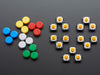 Top-down shot of 15 colorful round tactile button switches in green, yellow, red, blue, and white.