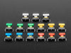 Angled  shot of 15 colorful square tactile button switches in green, yellow, red, blue, and white.