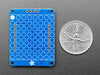 Back of blue, rectangular 8x8 LED matrix backpack add-on board next to US quarter for scale.