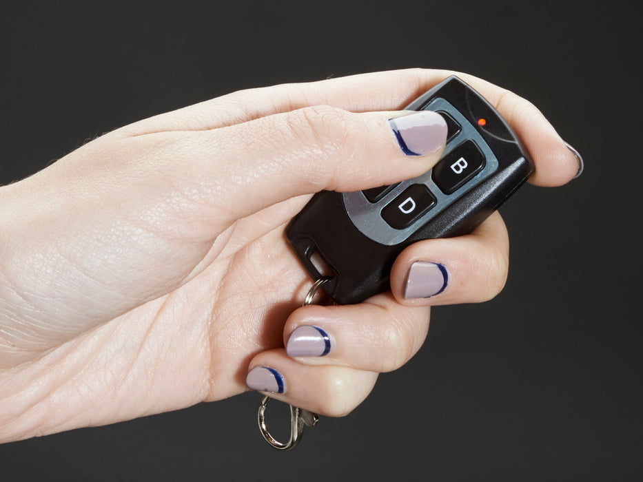 Hand pressing buttons on Keyfob 4-Button RF Remote Control and controlling LEDs on a project