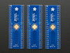 A pair of tweezers holding a microchip hovers over the SMT Breakout PCB for 44-QFN or 44-TQFP placement on a long blue rectangular breakout board.