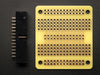 A white manicured hand holds up an assembled Adafruit Small-Size Perma-Proto Raspberry Pi Breadboard PCB.