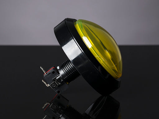 Head-on shot of illuminated massive yellow 100mm arcade button.