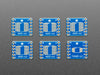 A pair of tweezers holding a microchip hovers over the SMT Breakout PCB for SOIC-12 or TSSOP-12. 