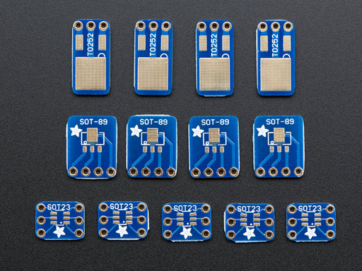 A pair of tweezers holding a microchip hovers over a small rectangular Breakout PCB.