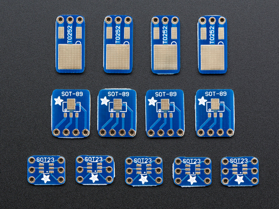 A pair of tweezers holding a microchip hovers over a small rectangular Breakout PCB.