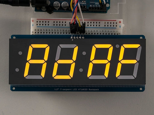 Huge yellow 7-segment clock display soldered to backpack with all segments lit