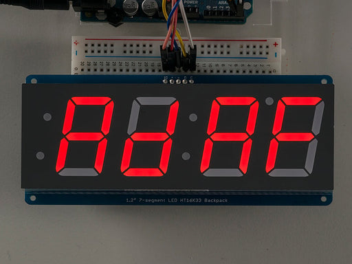 Huge red 7-segment clock display soldered to backpack with all segments lit