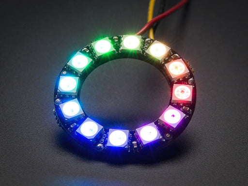 Hand holding NeoPixel Ring with 12  x 5050 RGB LED, lit up rainbow