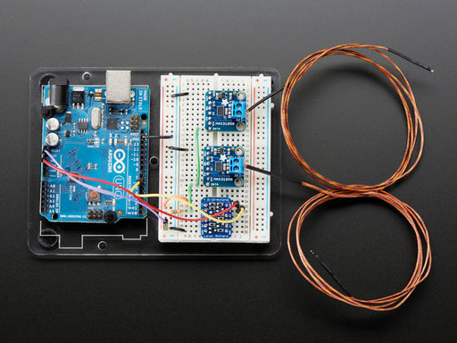 Top down view of a Thermocouple Amplifier with 1-Wire Breakout Board. Set of different kinds of headers to the left, a US quarter for scale to the right, and a resister below it. 