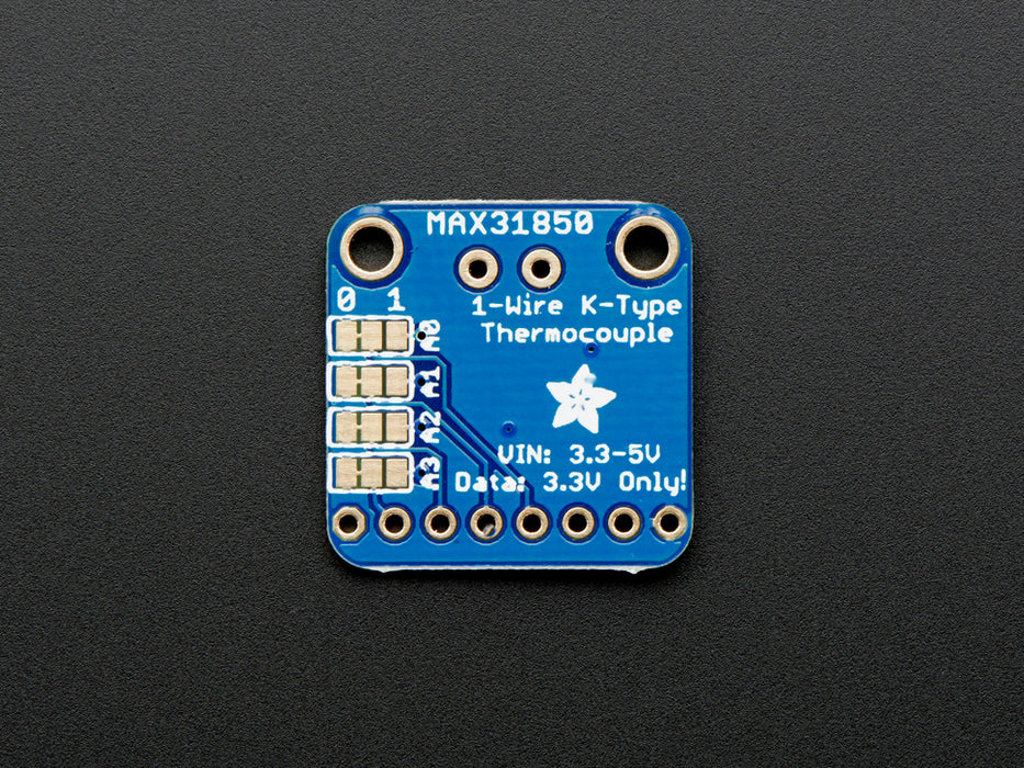 Top down view of a Thermocouple Amplifier with 1-Wire Breakout Board. Set of different kinds of headers to the left, a US quarter for scale to the right, and a resister below it. 