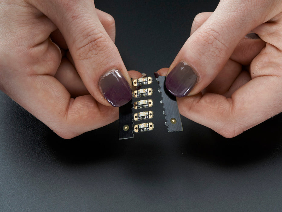 Single LED sequin PCB attached to two alligator clips, glowing green