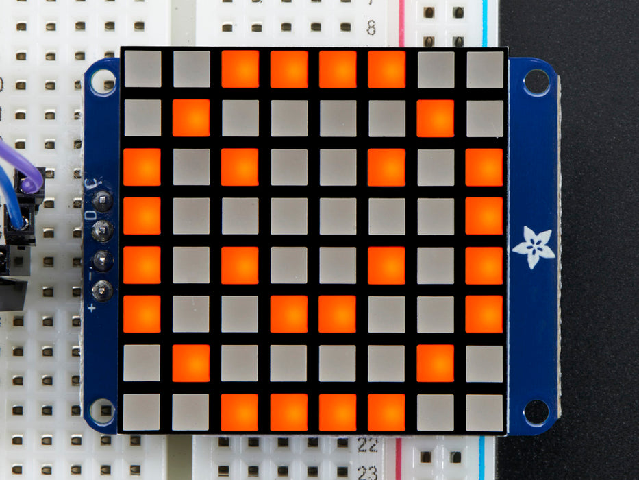 Close-up of Soldered and assembled Small 1.2" 8x8 Ultra Bright Square Amber LED Matrix + Backpack on a breadboard powered by an Arduino Uno. The LED Matrix displays an orange smiley.