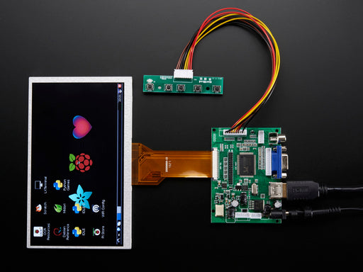 Angled shot of a HDMI 4 Pi: 7" Display no Touchscreen. The monitor displays a desktop background with a adafruit logo, raspberry logo, and a heart. 