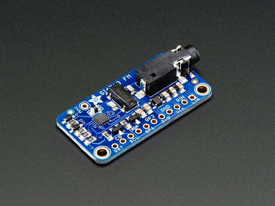 Top down view of a Adafruit Stereo FM Transmitter with RDS/RBDS Breakout next to a 11-pin header and under blue string coiled up.