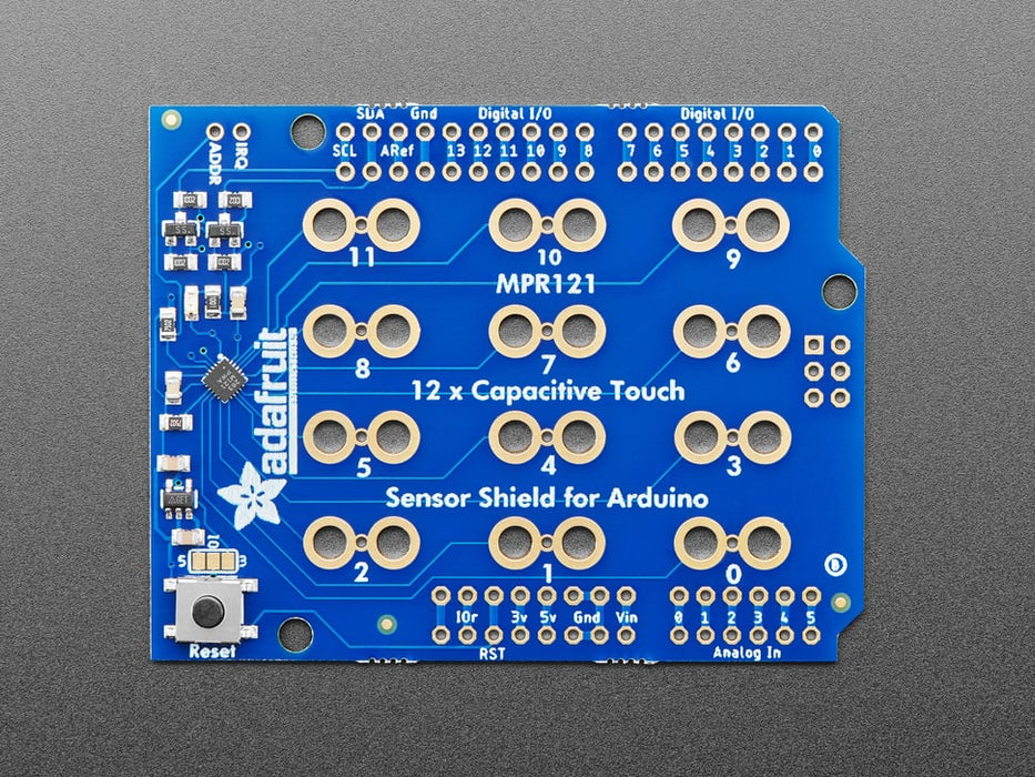 Top view of Capacitive Touch Shield for Arduino connected to various fruits and objects via alligator clips. 