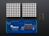 Close-up of Soldered and assembled 16x8 1.2" LED Matrix + Backpack - Ultra Bright Square Blue LEDs on a breadboard. The LED Matrices display a smiling emoji and a frowning emoji.