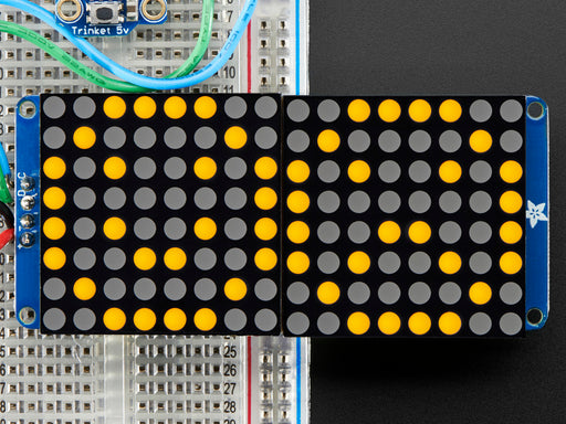 Close-up of Soldered and assembled 16x8 1.2" LED Matrix + Backpack - Ultra Bright Square Orange LEDs on a breadboard. The LED Matrices display a smiling emoji and a frowning emoji.