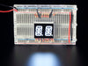 White Dual Alphanumeric Display module wired to breadboard, all segments lit