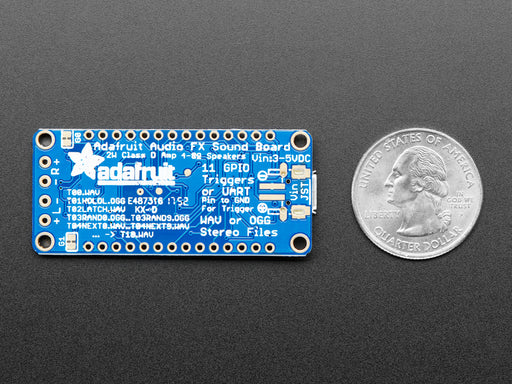 A long blue rectangular audio FX sound board assembled onto two half-size breadboards. The board is wired up to a 3 x AA battery pack and two speakers. A white hand presses a row of small tactile buttons wired up to the audio board.