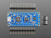 A long blue rectangular audio FX sound board assembled onto two half-size breadboards. The board is wired up to a 3 x AA battery pack and two speakers. A white hand presses a row of small tactile buttons wired up to the audio board.