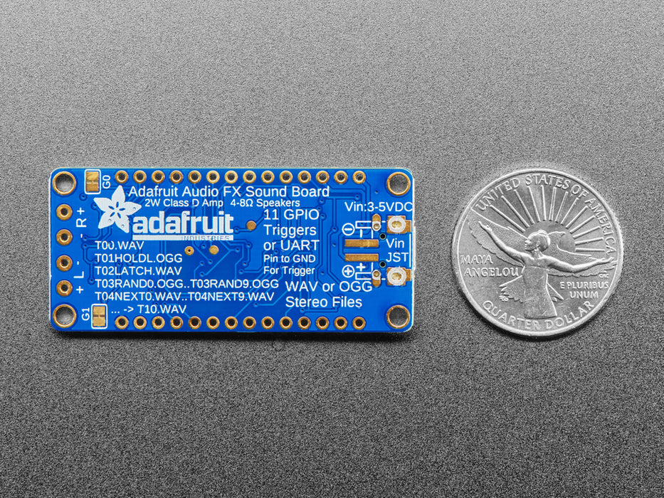 A long blue rectangular audio FX sound board assembled onto two half-size breadboards. The board is wired up to a 3 x AA battery pack and two speakers. A white hand presses a row of small tactile buttons wired up to the audio board.