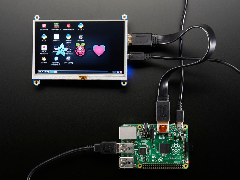 Black polished finger touching the display of a HDMI 5" Display Backpack. The HDMI screen displays a desktop image including the Adafruit logo, the Raspberry Pi logo, and a pink heart.