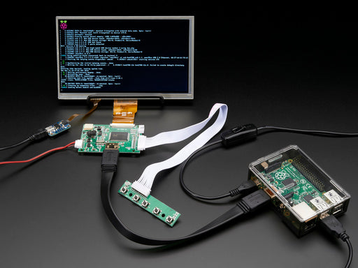 Front shot of a HDMI 4 Pi: 7" Display connected to a Raspberry Pi. The monitor displays a desktop background with a adafruit logo, raspberry logo, and a heart. 