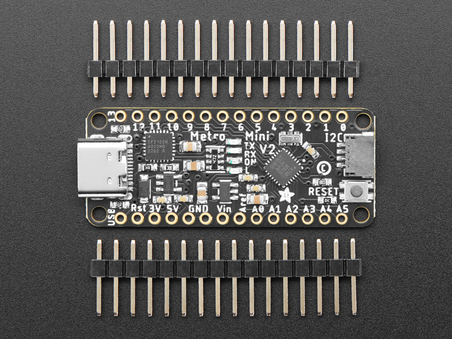 Overhead shot of long skinny black microcontroller connected to an OLED screen and a temperature-and-humidity sensor. The sensor data displays on the OLED.