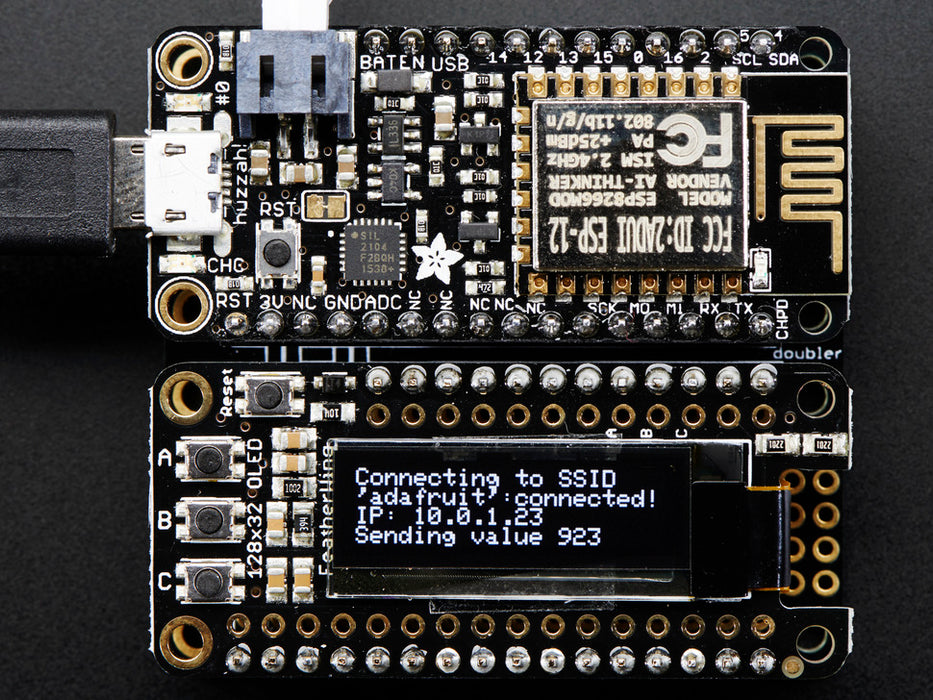 Angled shot of a Adafruit FeatherWing OLED - 128x32 OLED Add-on For Feather connected to a white breadboard and a lithium battery. 