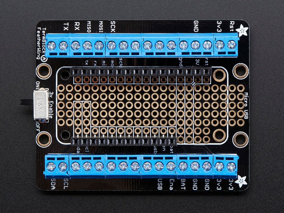 Angled shot of an Assembled Terminal Block Breakout FeatherWing for all Feathers with black headers. 