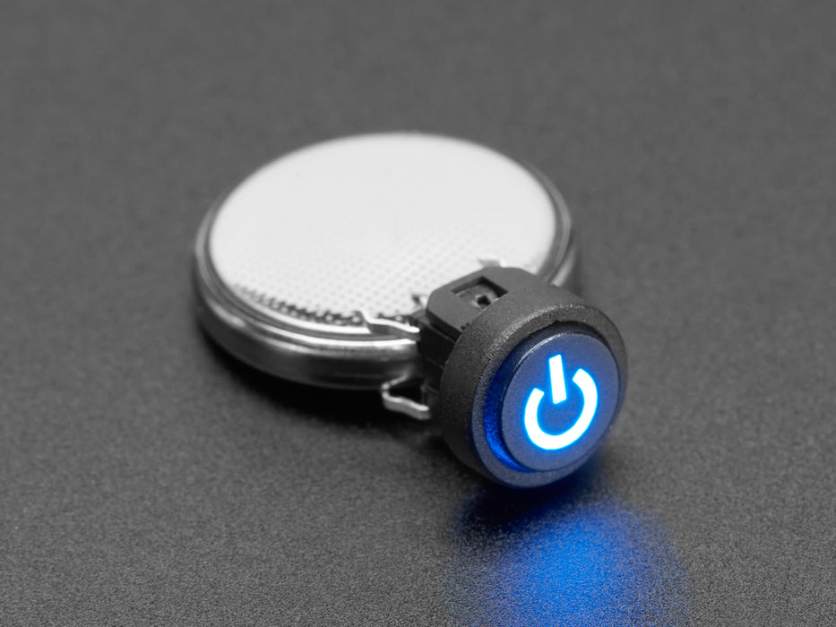 Close-up of a mini illuminated push-button with a blue power symbol installed in a half-size breadboard. Also are on the breadboard are two jumper wires and a resistor.