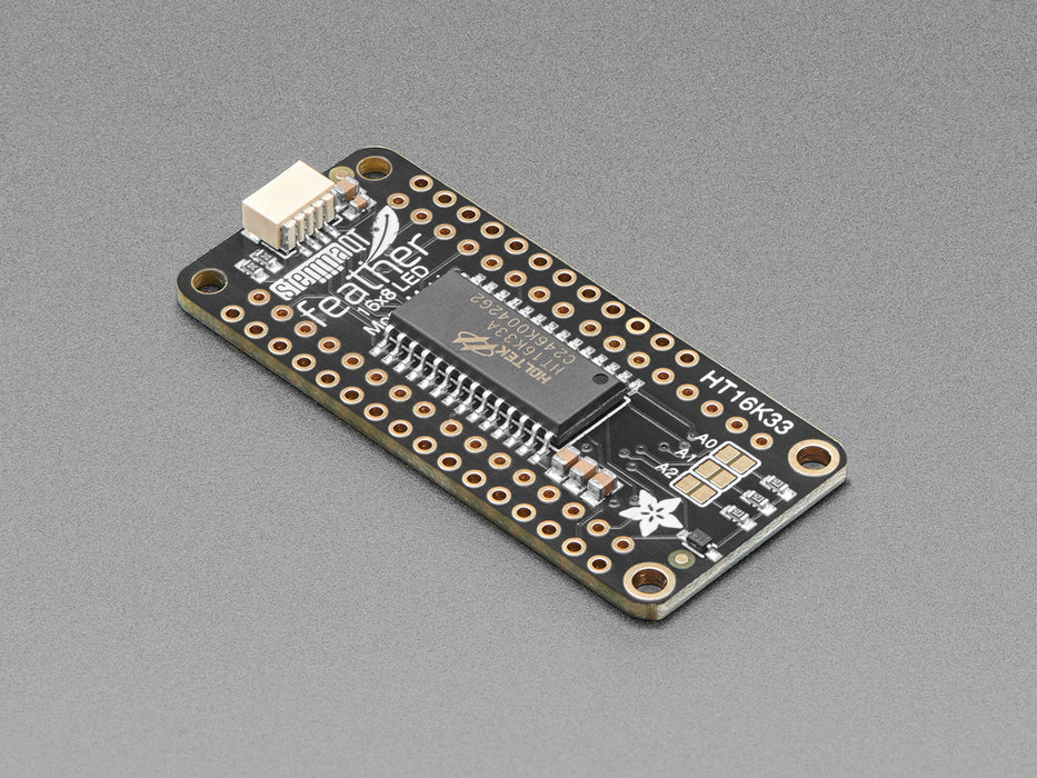 Angled shot of a rectangular shaped LED Matrix FeatherWing Display Kit breakout board with an LED matrix soldered on.