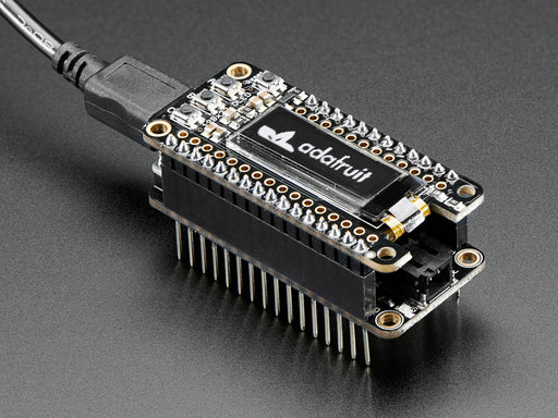 Angled shot of a black rectangular microcontroller adapter board assembled with an even smaller green microcontroller board.