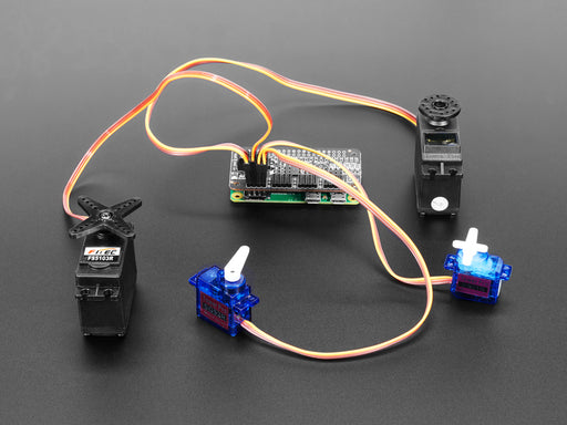 Angled shot of a Adafruit 16-Channel PWM / Servo Bonnet for Raspberry Pi stacked on a Raspberry Pi Zero connected to 4 different kinds of Servos. 