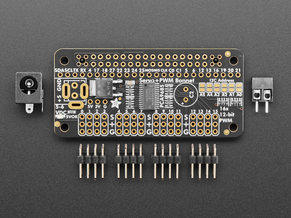 Angled shot of a Adafruit 16-Channel PWM / Servo Bonnet for Raspberry Pi stacked on a Raspberry Pi Zero connected to 4 different kinds of Servos. 