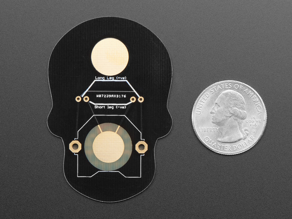 Angled shot of a Dia de los Muertos skull PCB with red glowing LEDs for eyes.