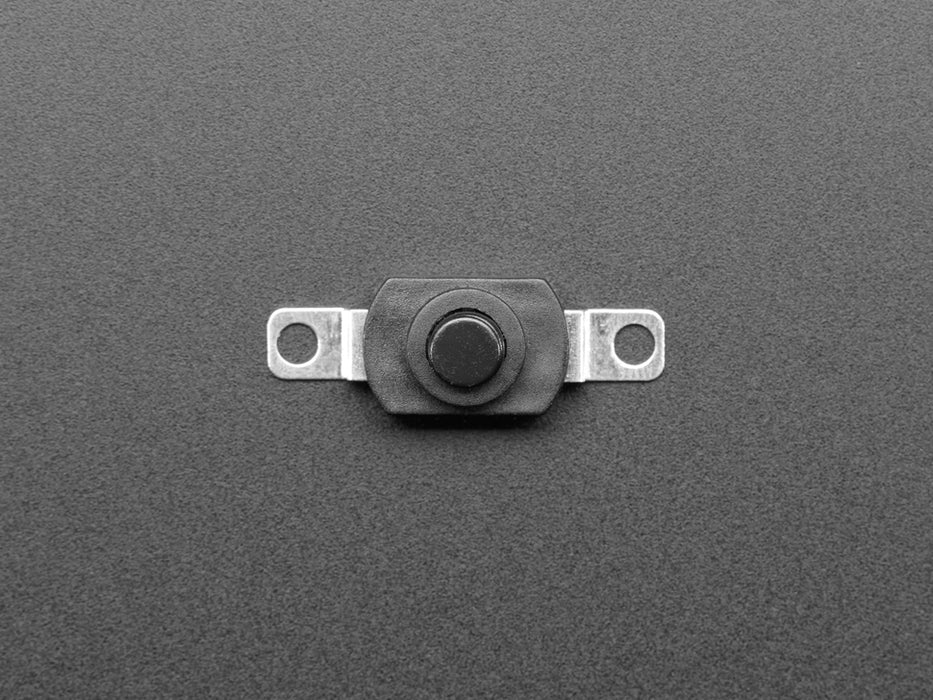 Angled shot of black mini on/off pushbutton switch with two mounting holes.