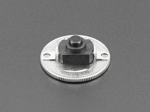 Angled shot of black mini on/off pushbutton switch with two mounting holes.