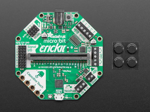 Angled shot of a Adafruit CRICKIT for micro:bit connected to a black squared board.