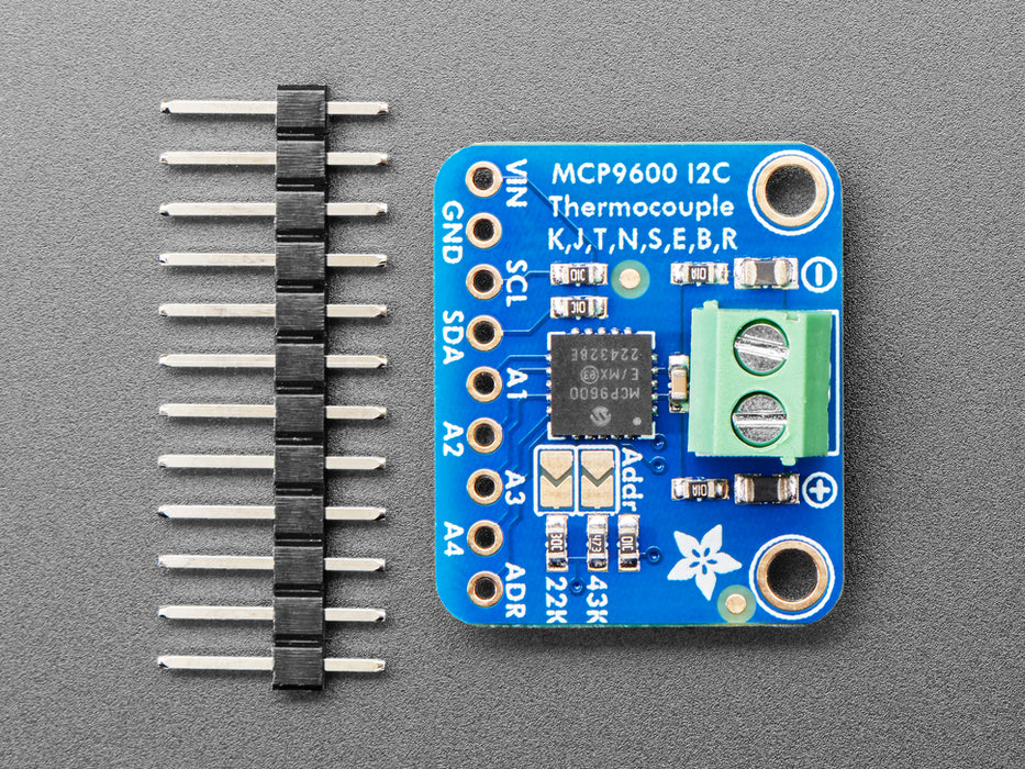 Angled shot of a square, blue, thermocouple amplifier with a green terminal block.