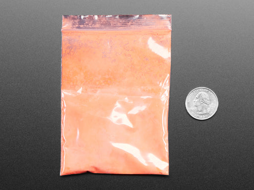 Angled shot of plastic baggy containing orange thermochromic pigment powder.