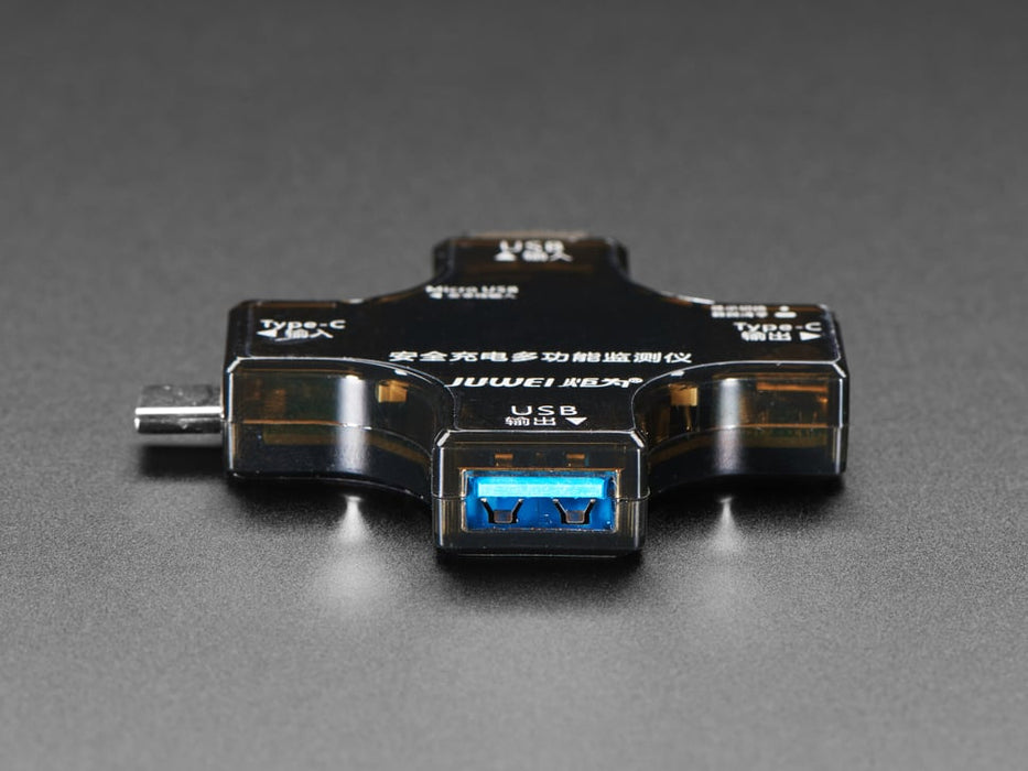 Top view of multifunctional USB tester connected to a laptop. The display reads voltage and current information.