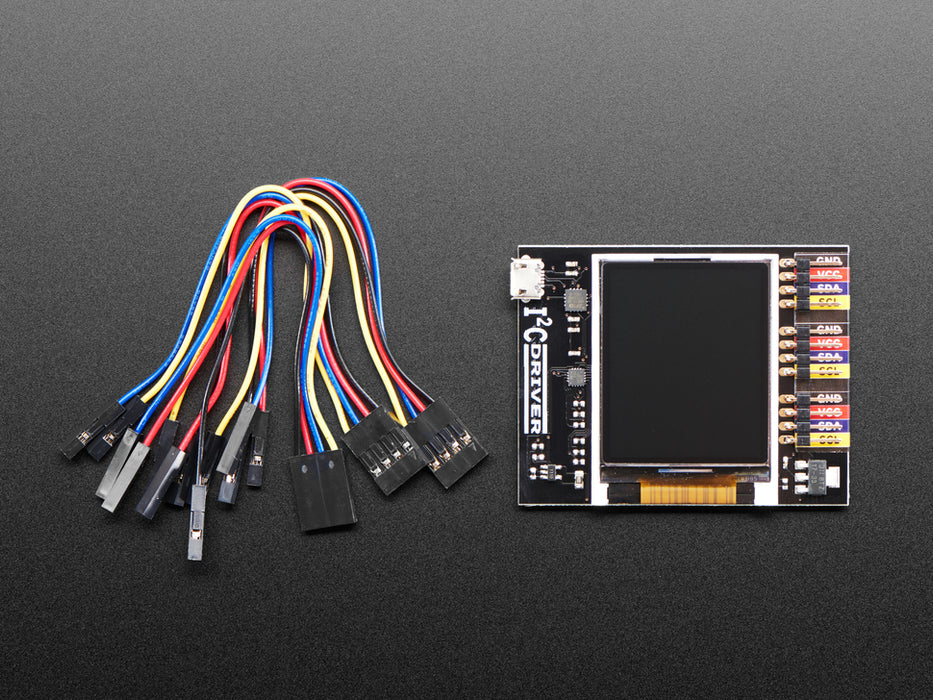 Top down view of a  I2CDriver by Excamera Labs attached to a small blue squared breakout board being held by a white hand. 