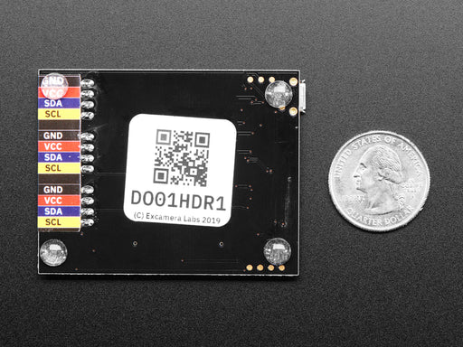 Top down view of a  I2CDriver by Excamera Labs attached to a small blue squared breakout board being held by a white hand. 