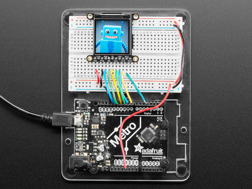 Overhead shot of 1.3" TFT breakout connected via EYESPI board and microcontroller on a half-size breadboard. The TFT breakout displays a colorful hexagon.