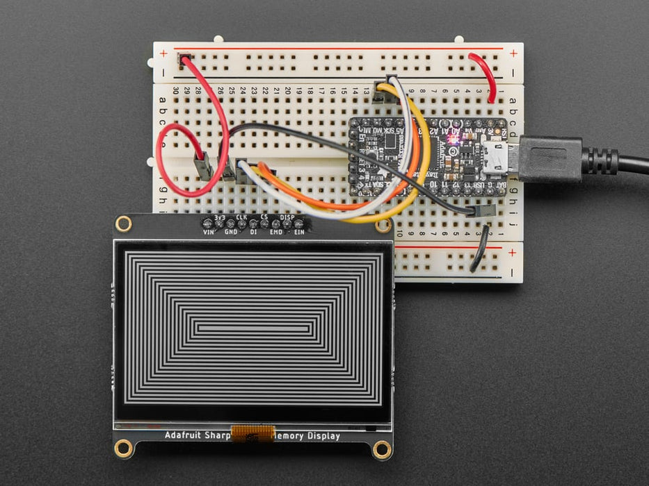 Adafruit SHARP Memory Display Breakout connected to a half-sized breadboard and a microcontroller. The breakout board plays a black and white animation video of black figures playing violins and a keyboard.