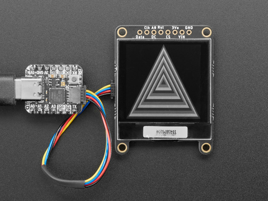 Monochrome OLED module wired to QT Py showing falling Adafruit logos