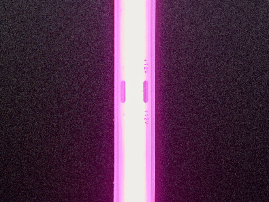 Two hands repeatedly bending and manipulating lit-up flexible pink LED strip